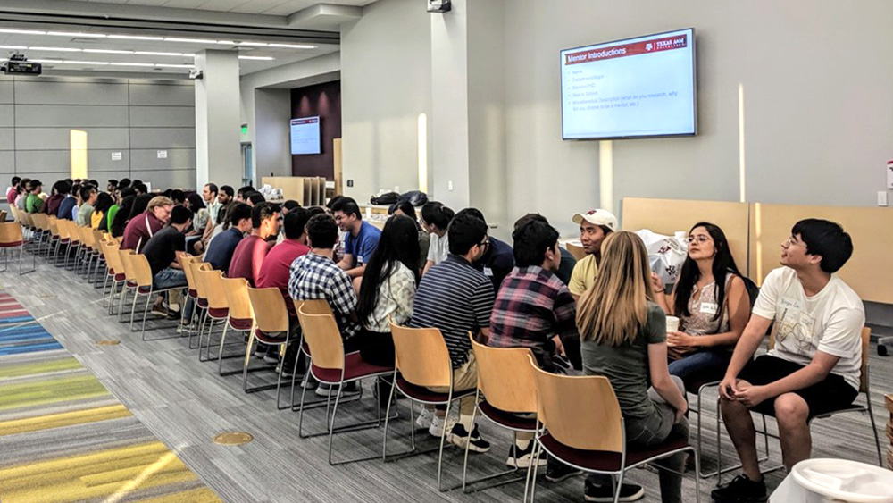 a large group of students sit in chairs facing each other