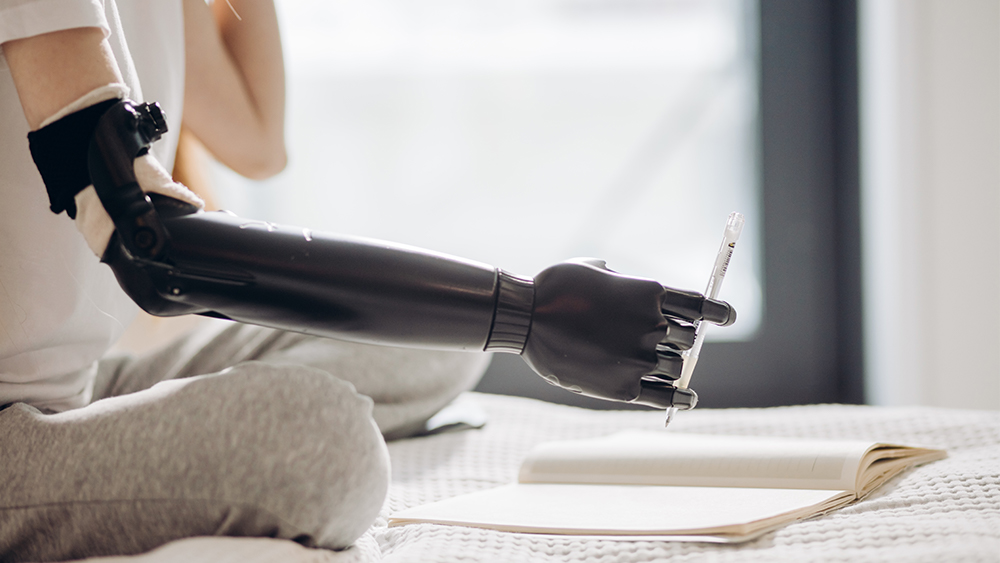 Individual uses an upper arm prosthetic to hold a pen. 