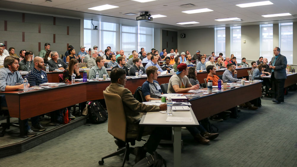 A guest speaker lecturing to an audience at the dredging short course