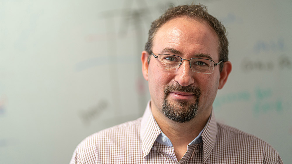 Dr. Eduardo Gildin standing before white board with calculations related to drilling advisory system research for the Department of Energy