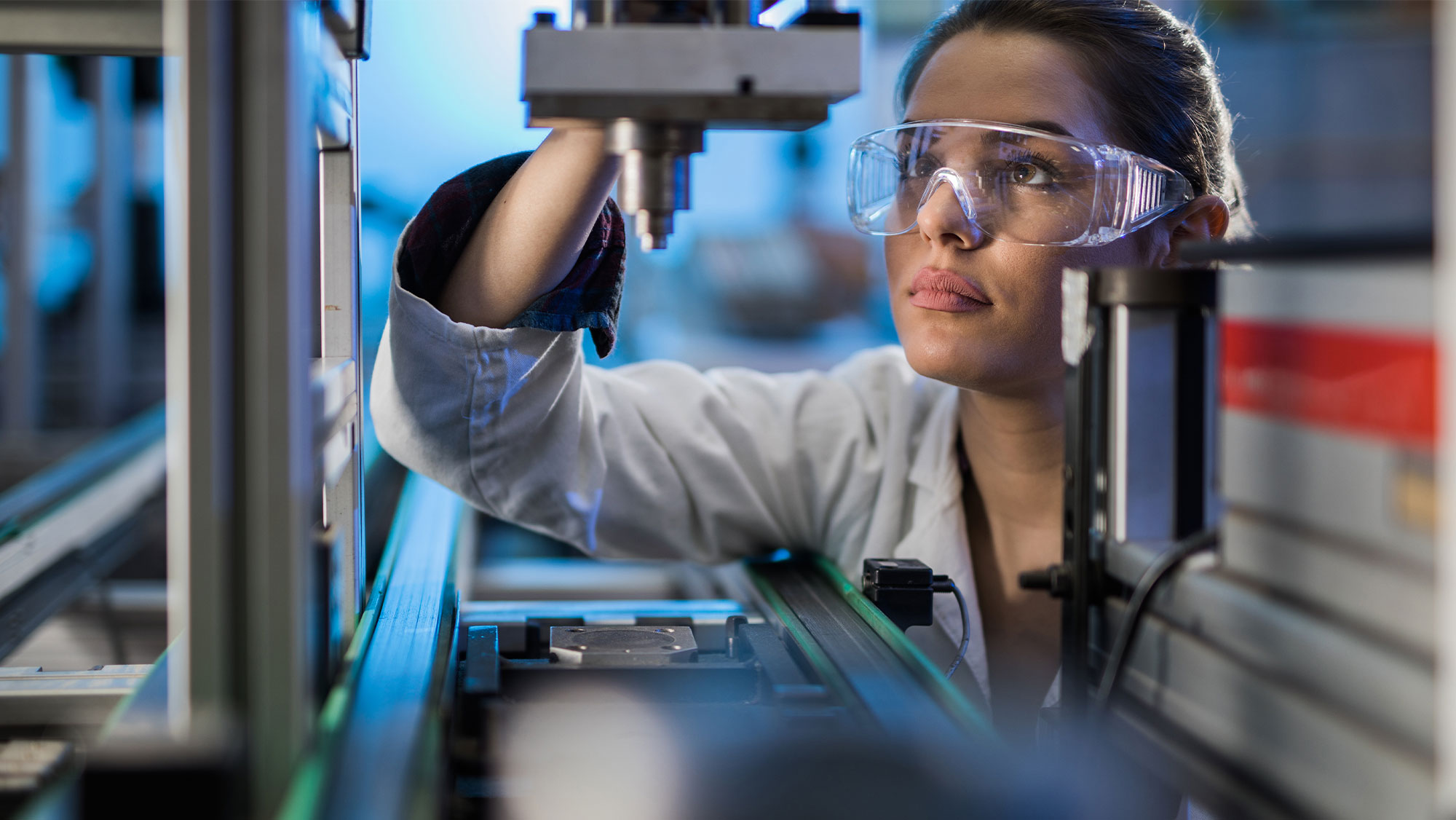 Female engineer examining machine part on a production line.