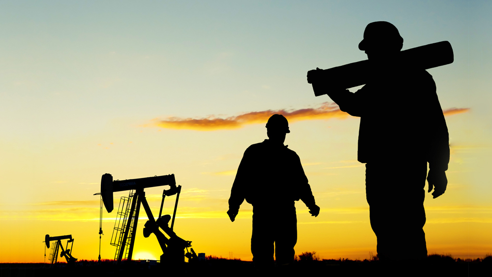 Oil field works on well site with pump jacks in the background.