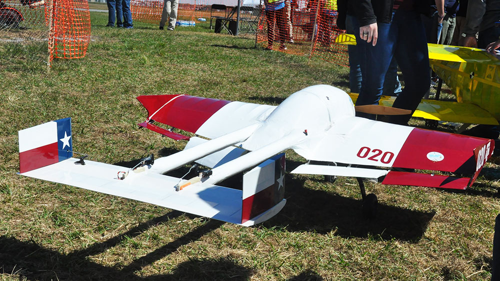 TAMU SAE team poses with their small-winged aircraft next to competitors and their large aircrafts.