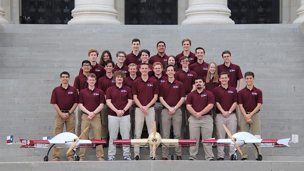 TAMU SAE team, Farmers Flight, posed in their maroon team polos next to three of their aircrafts.