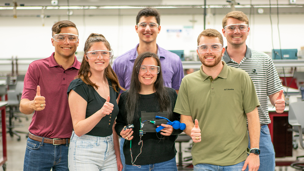 Capstone team holding its seizure alert system. 