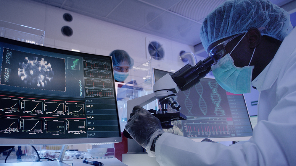 Man looking into the microscope with monitors in front of him