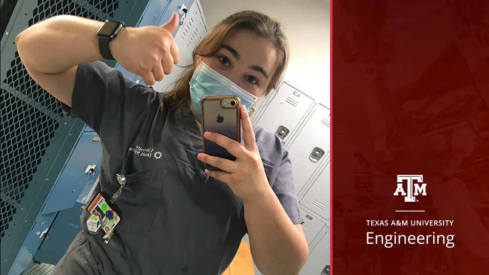 Kaya Mariello stands in scrubs and a mask. She is holding up a gig 'em sign with her hand. 