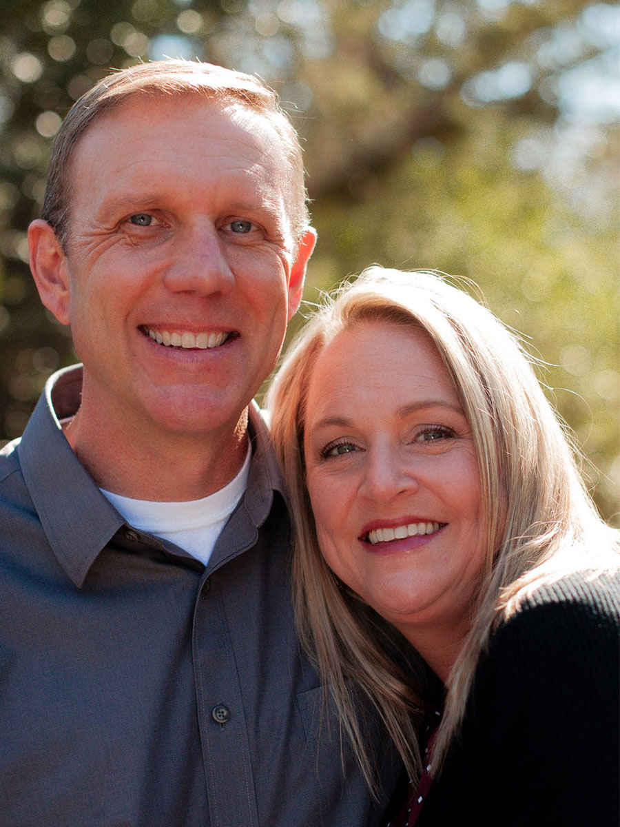 Lori and Blake Alexander posing for a photo in front of a tree. 