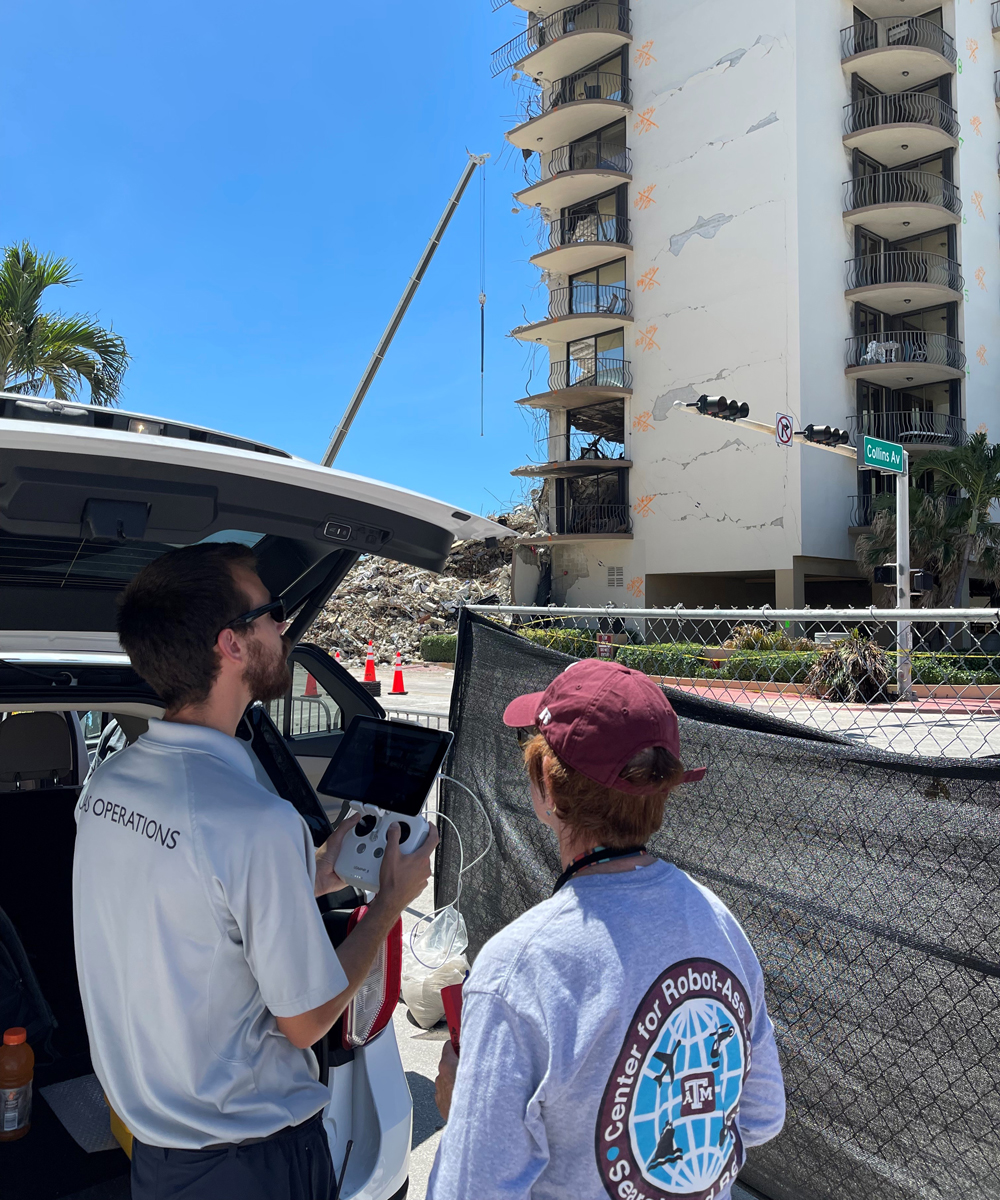 Dr. Robin Murphy standing beside Austin Bush as he operates a drone at the site of the Champlain Towers South Condo building collapse.