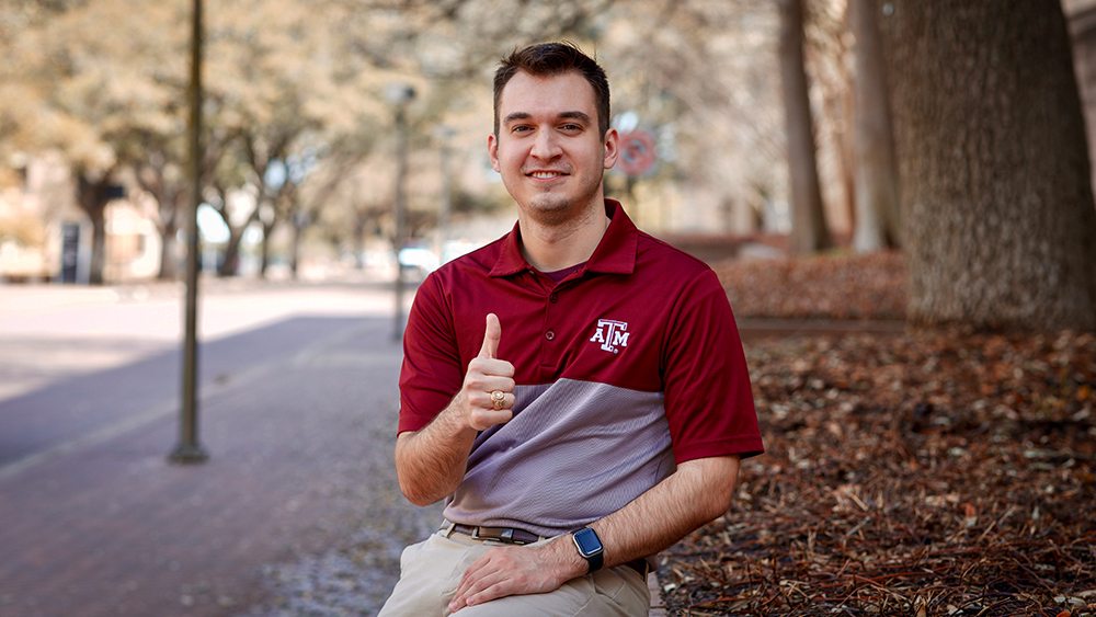 Former student Andrew Balog ‘21 sits under a tree outside