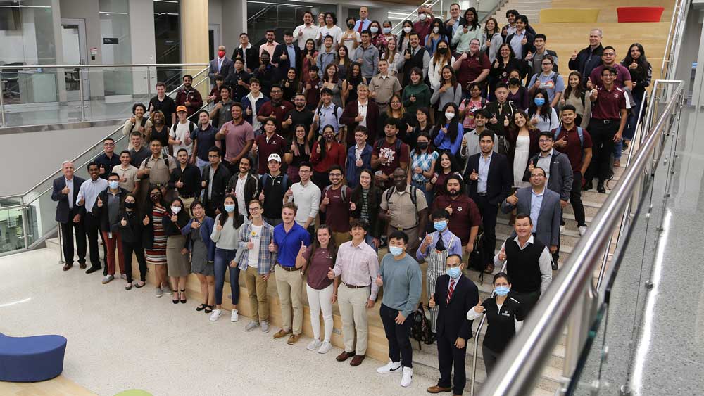 A group of students and professors with a thumbs up.