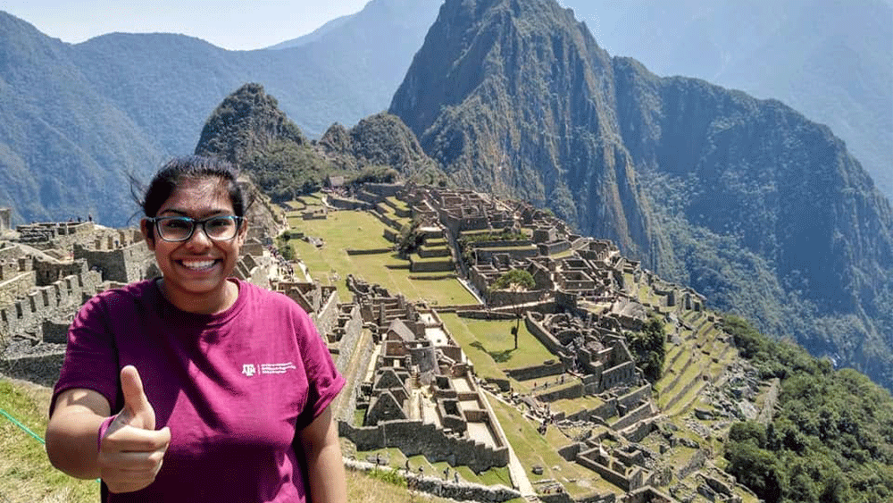 Woman with thumbs up in front of hills.