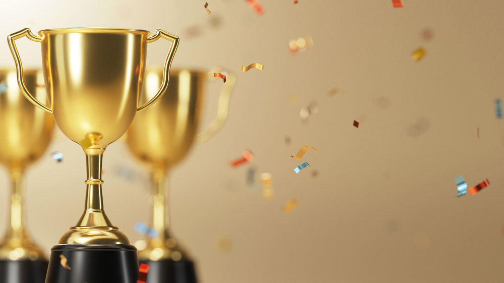 Multi-colored metallic confetti falling around three gold trophies.