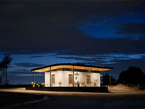 A nighttime exterior photo of ICON's 3D-Printed Welcome Center Community in Austin Texas. 