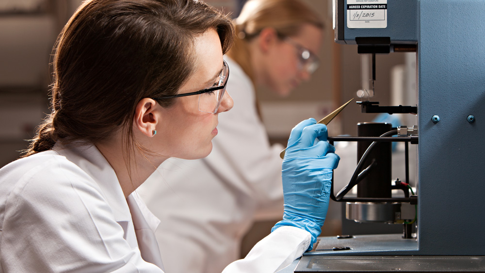 Two female graduate student researchers wearing protective gear use equipment in a biomedical engineering lab at Texas A&M University