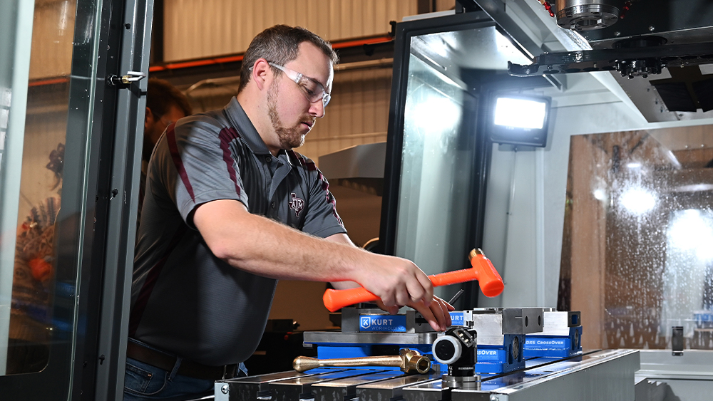 Tobias Gualandri holds mallet-shaped tool and works with machinery to tighten vise jaws.