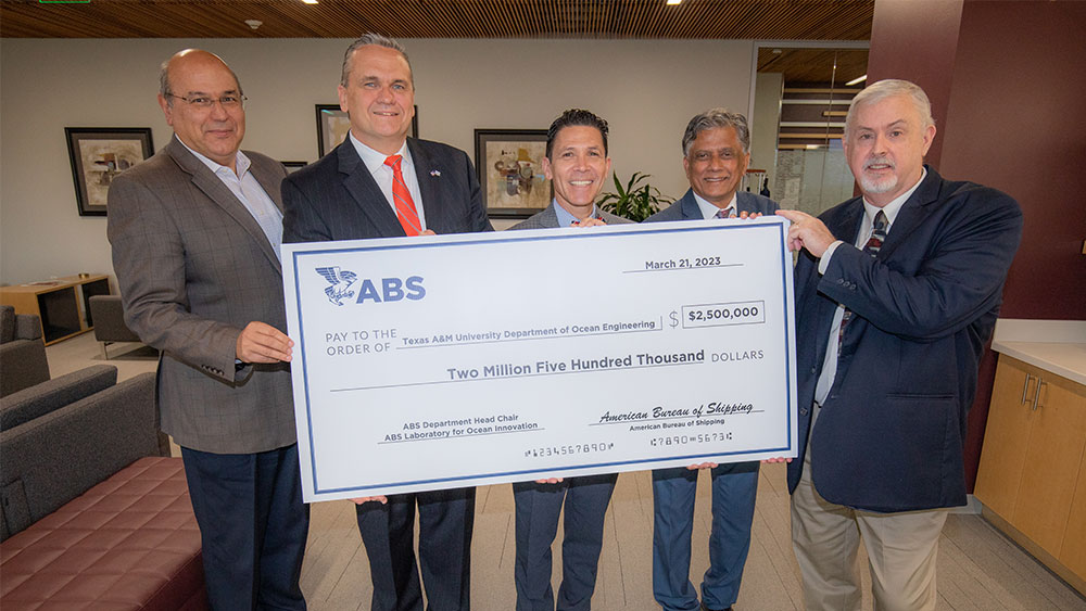 Five gentlemen posing for a photo holding a giant money check