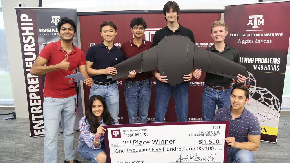 Seven students from Team Sky Guardians holding their third-place oversized check for $1,500.