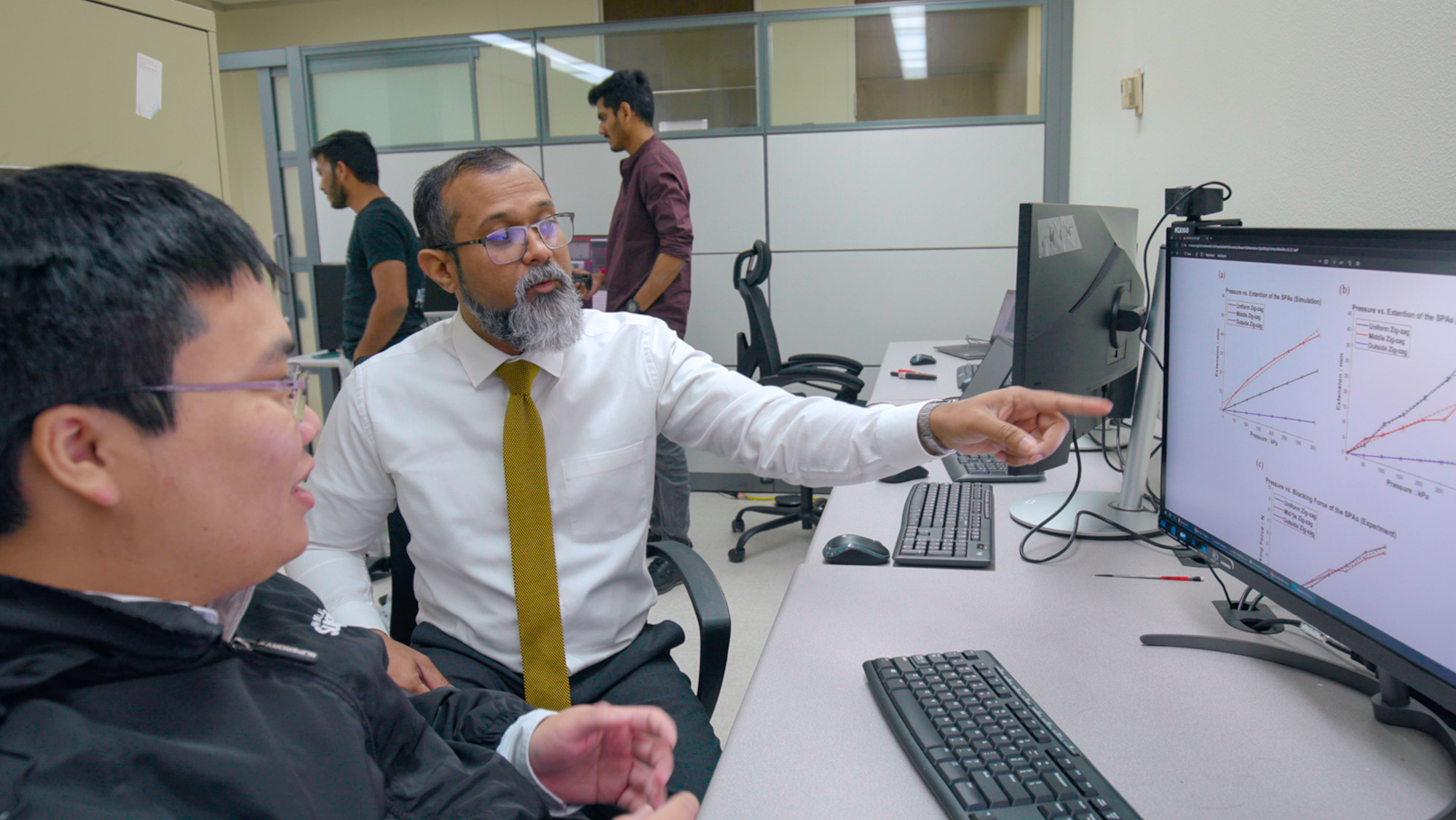 Dr. Isuru Godage works with students in his lab.