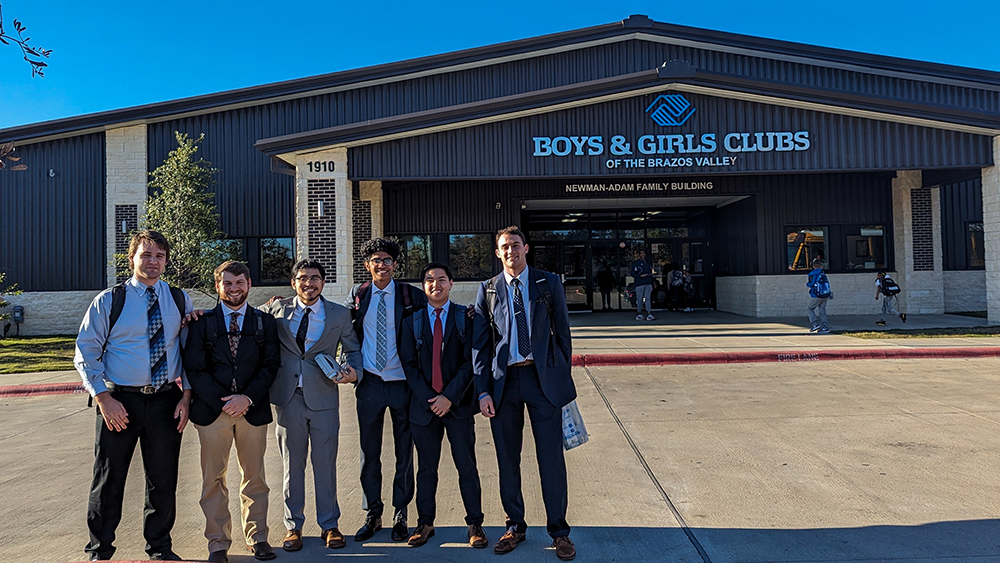 Six men standing in front of a building that says “Boys and Girls Club of the Brazos Valley.”