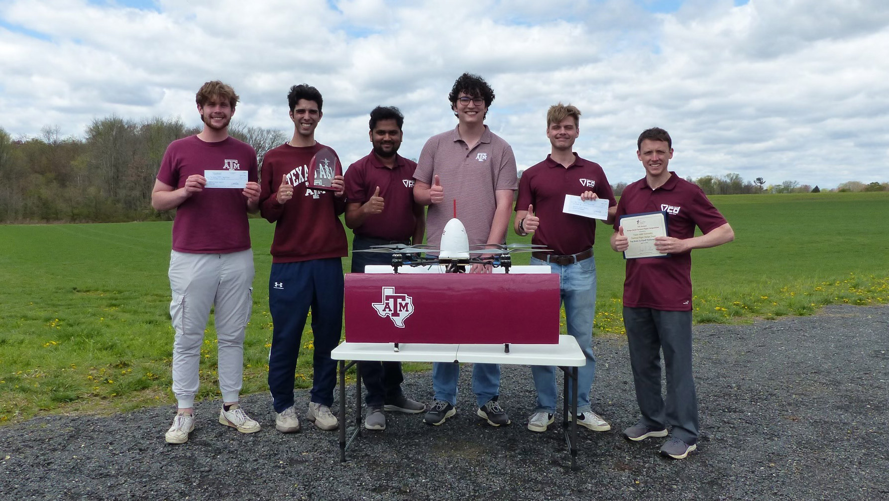 A group of men standing in front of a quadcopter biplane.