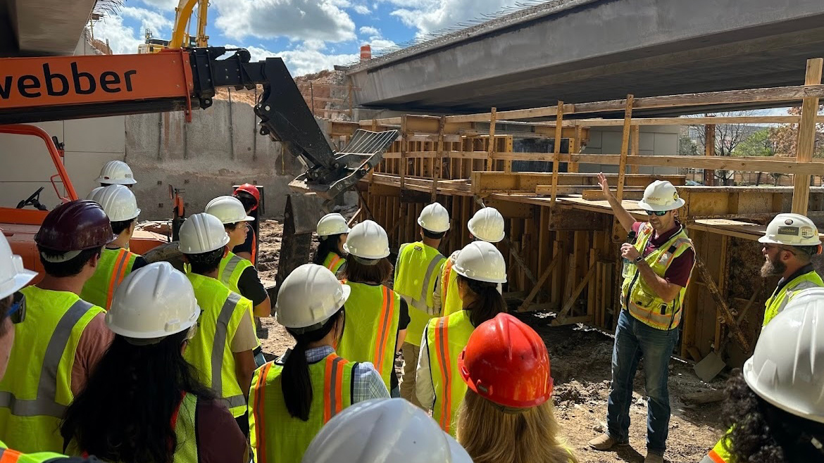 A group of people in construction jackets at a construction site. 