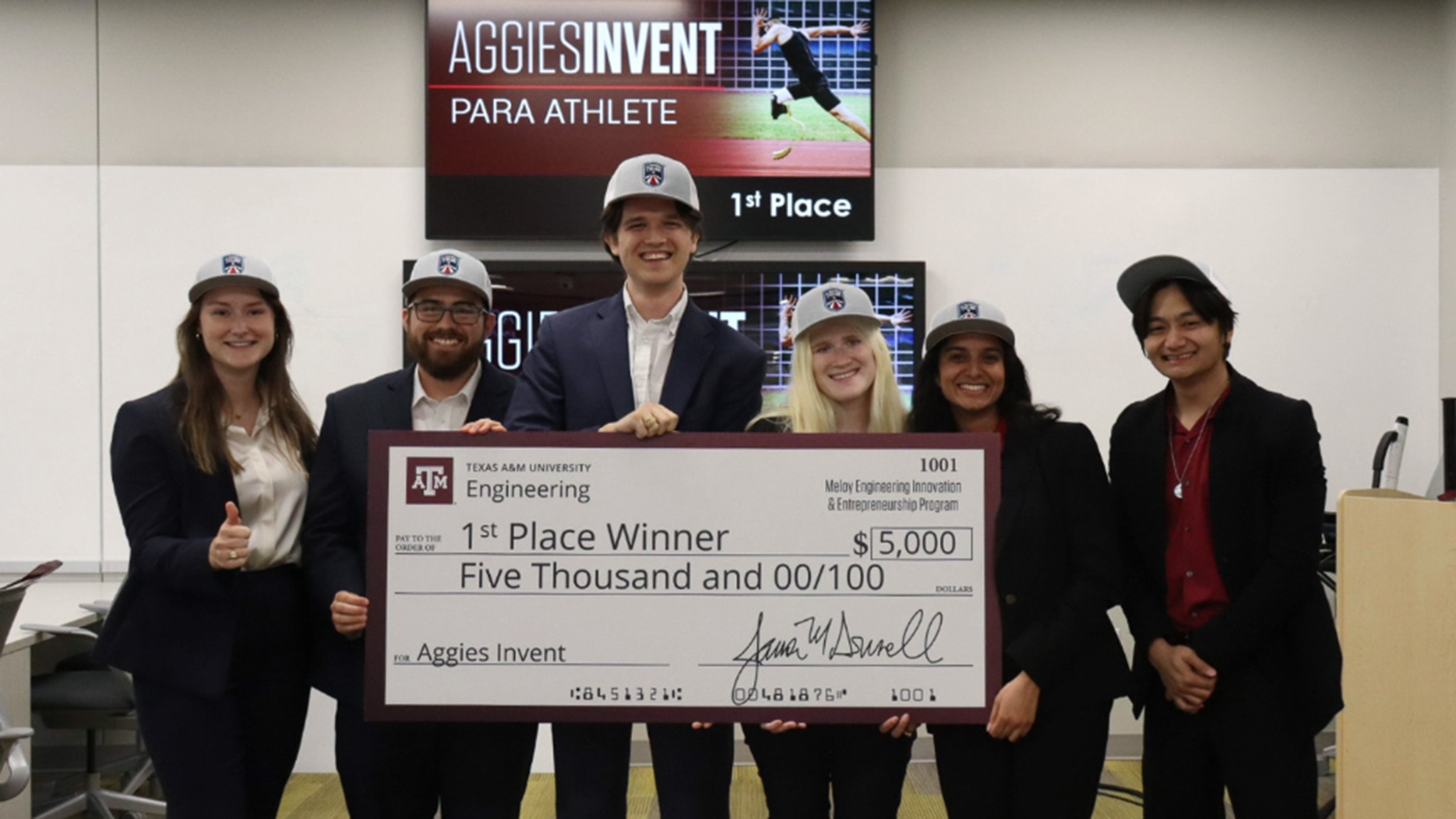 Students holding a large check for $5,000 that says 1st Place Winner.