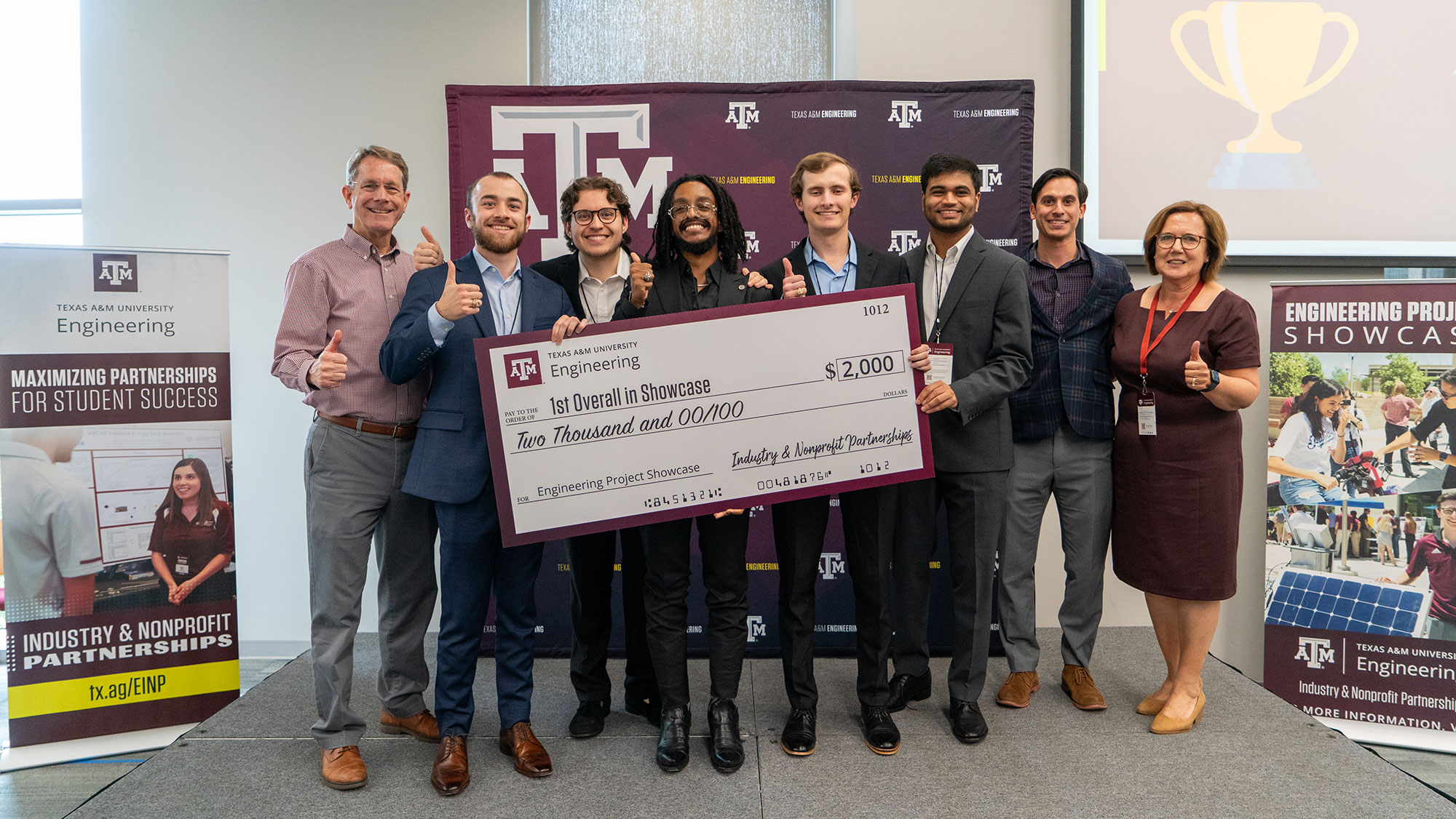 Eight people stand by a large check for $2,000.