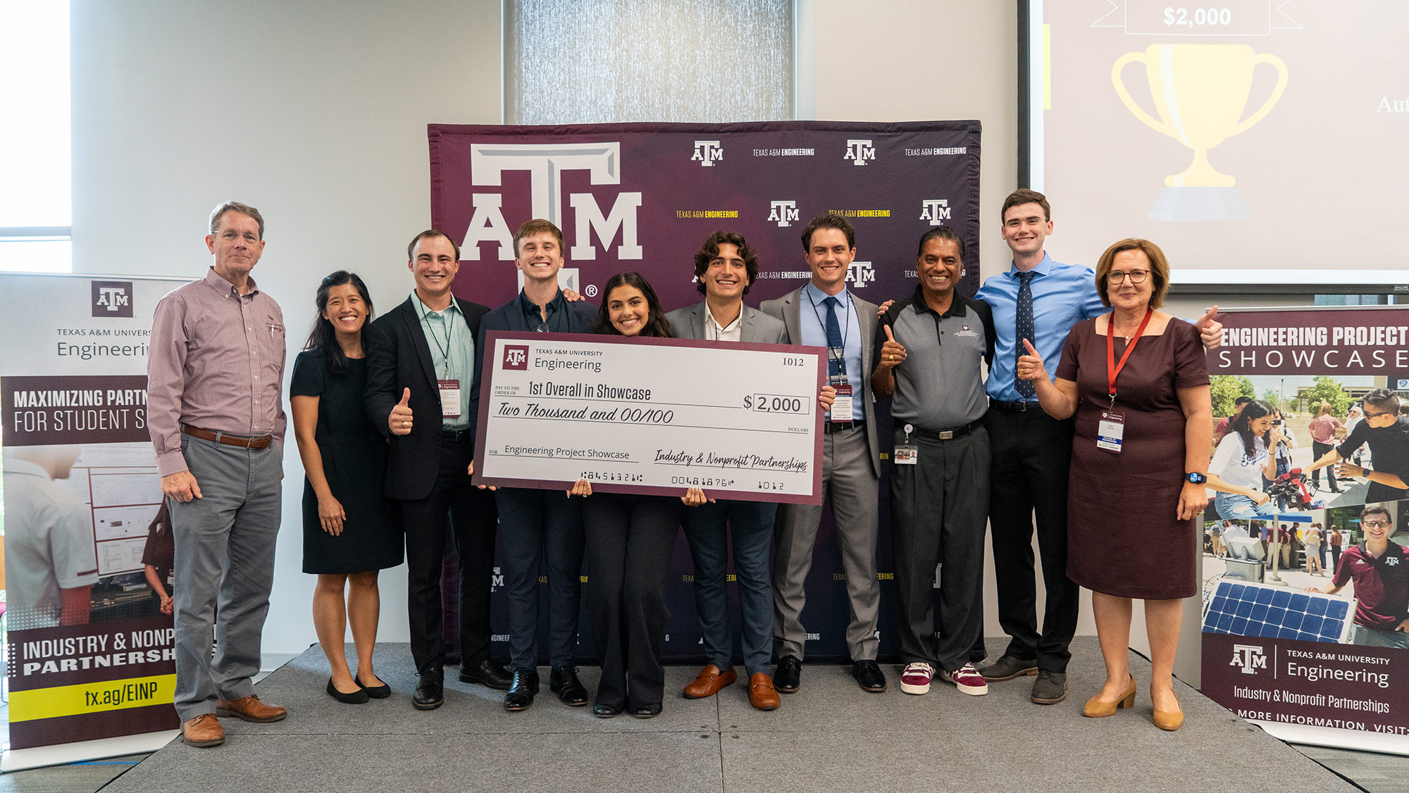 10 people stand by a large check for $2,000. 