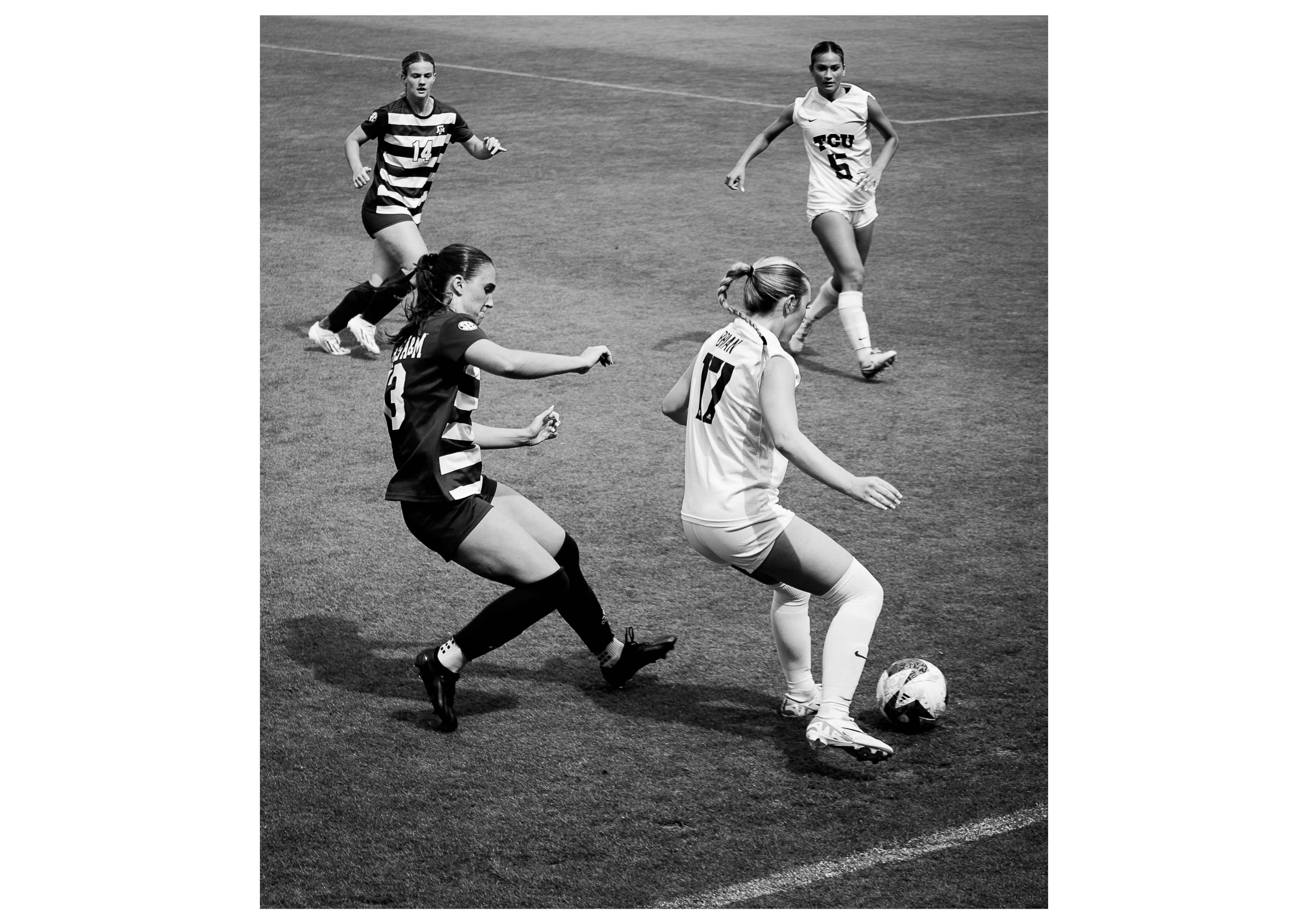 A black and white image of four women playing soccer.