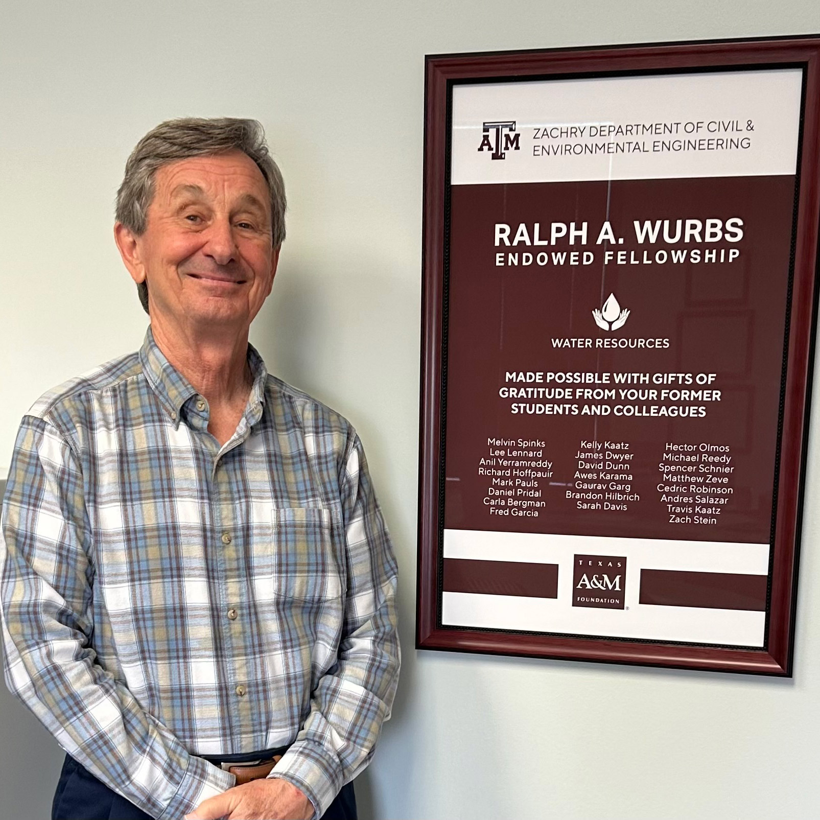 A man poses with a framed poster.