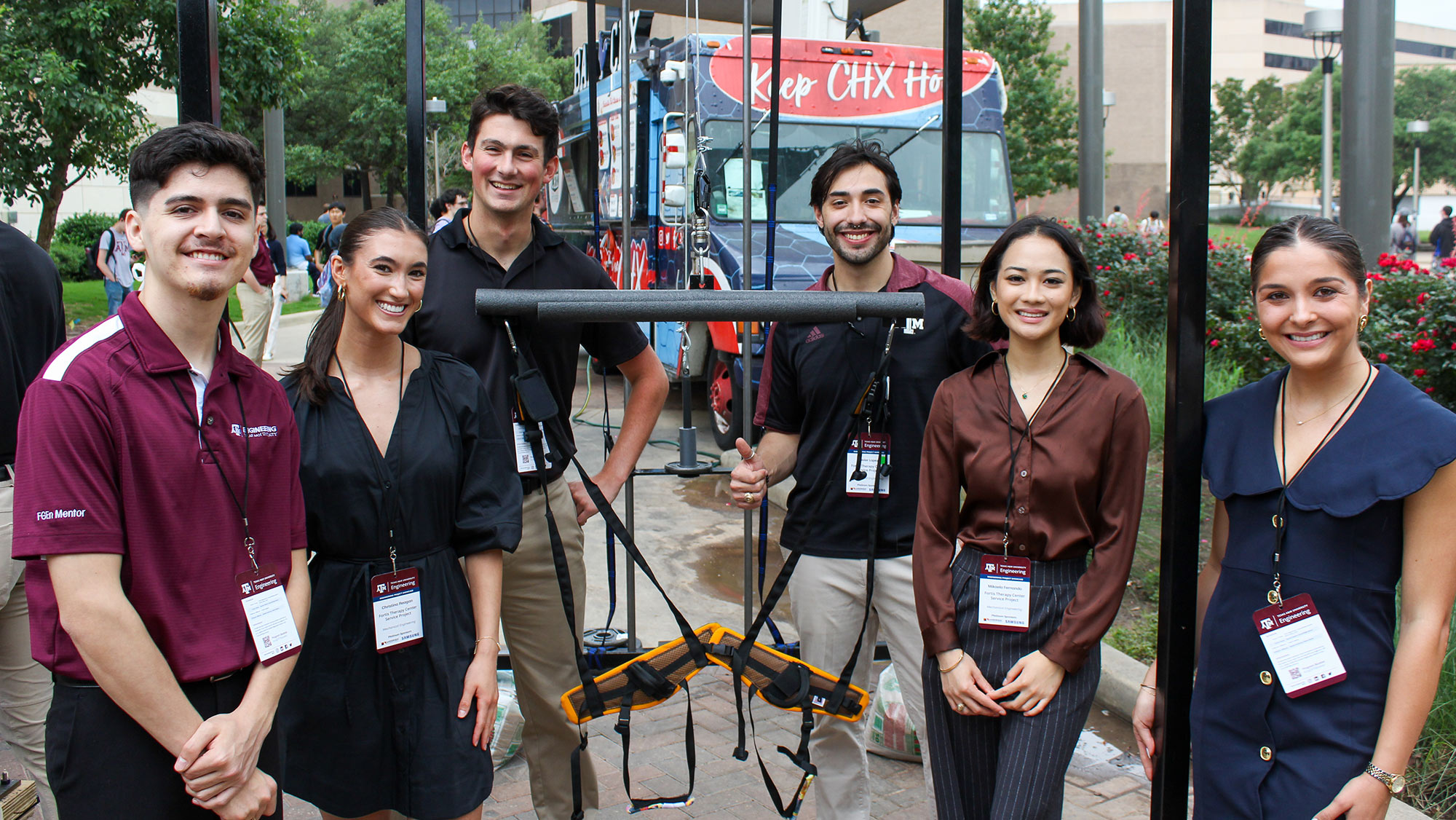 A group of six adults standing outdoors at a professional event beside a mobility device.