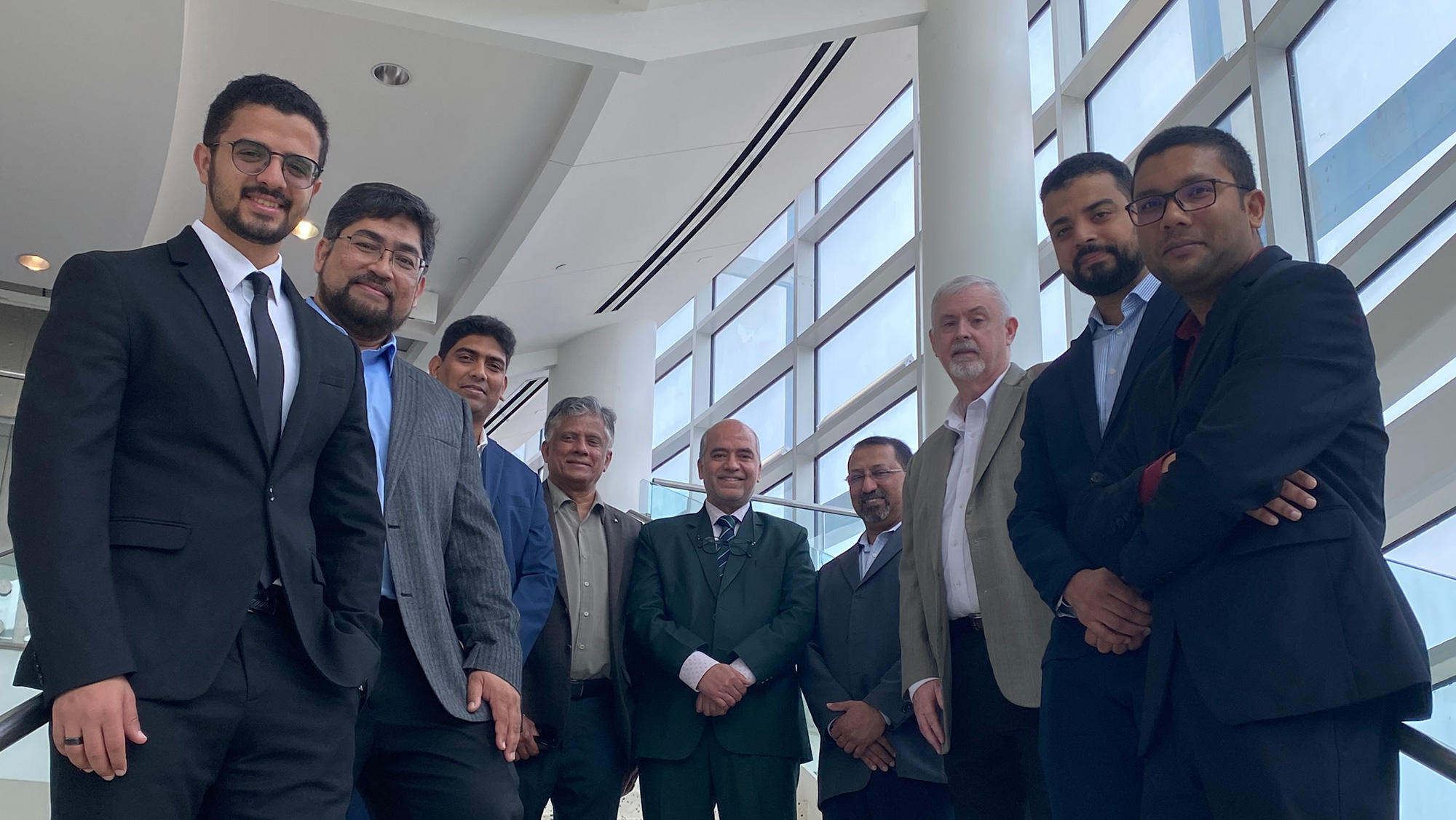 Nine men standing on stairs.