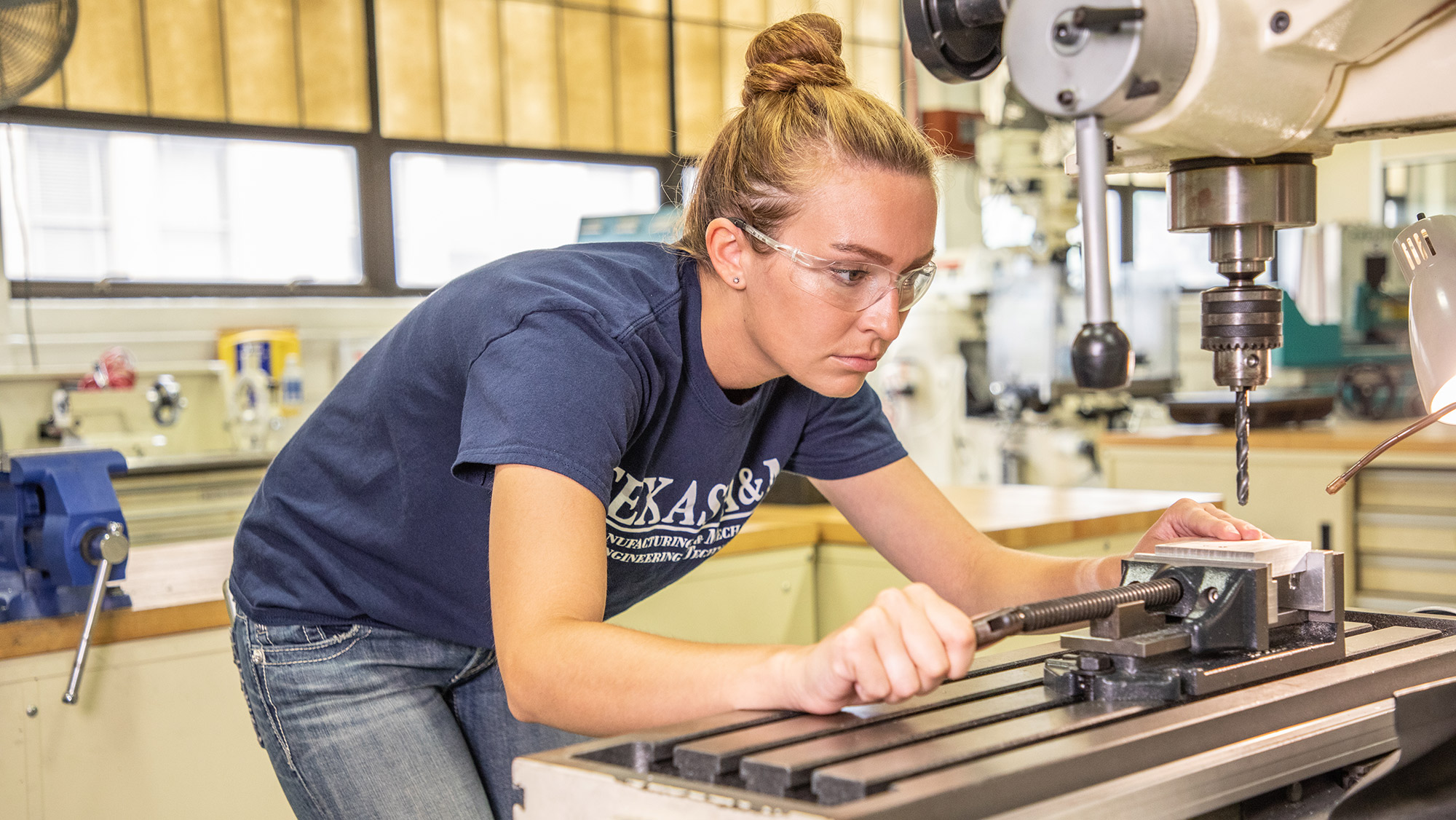 A woman wearing safety glasses works in an engineering lab.