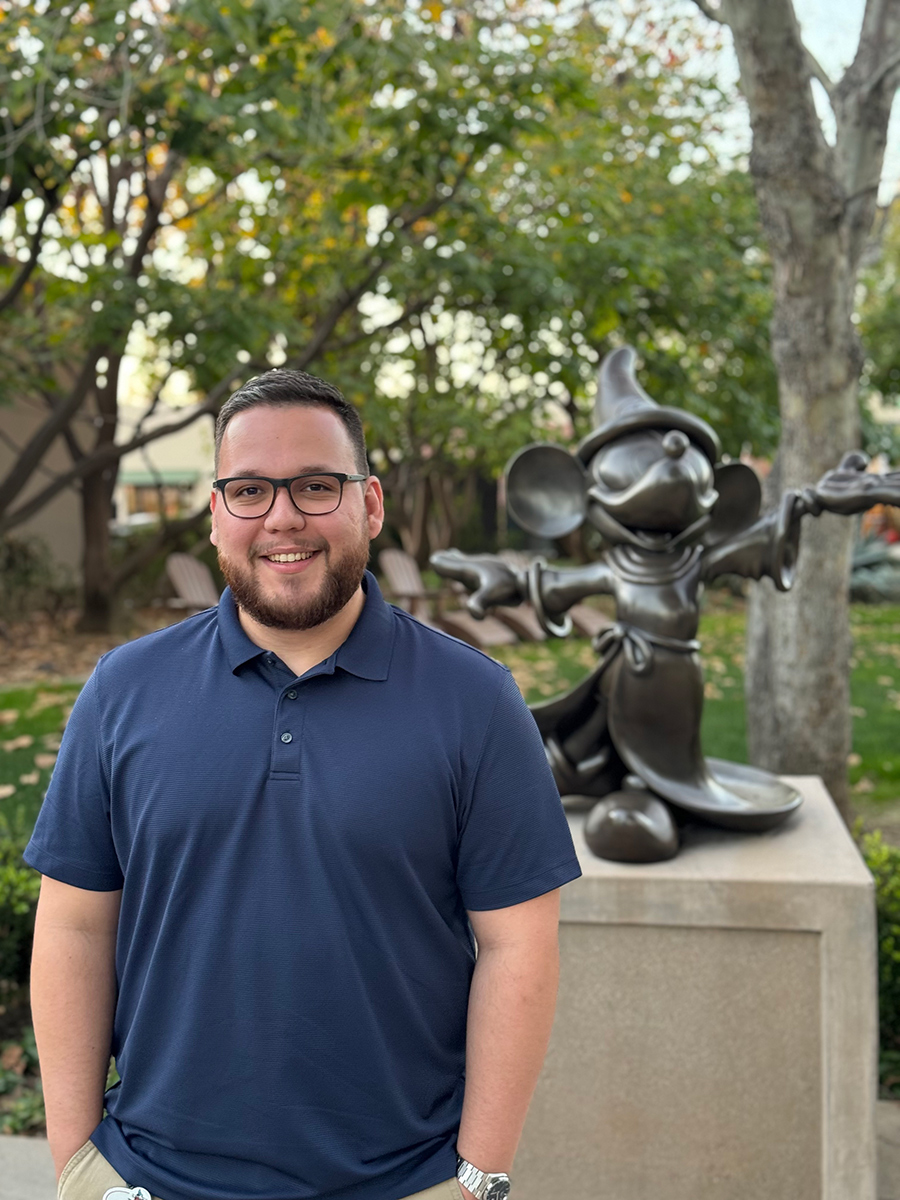 Man posing in front of statue.