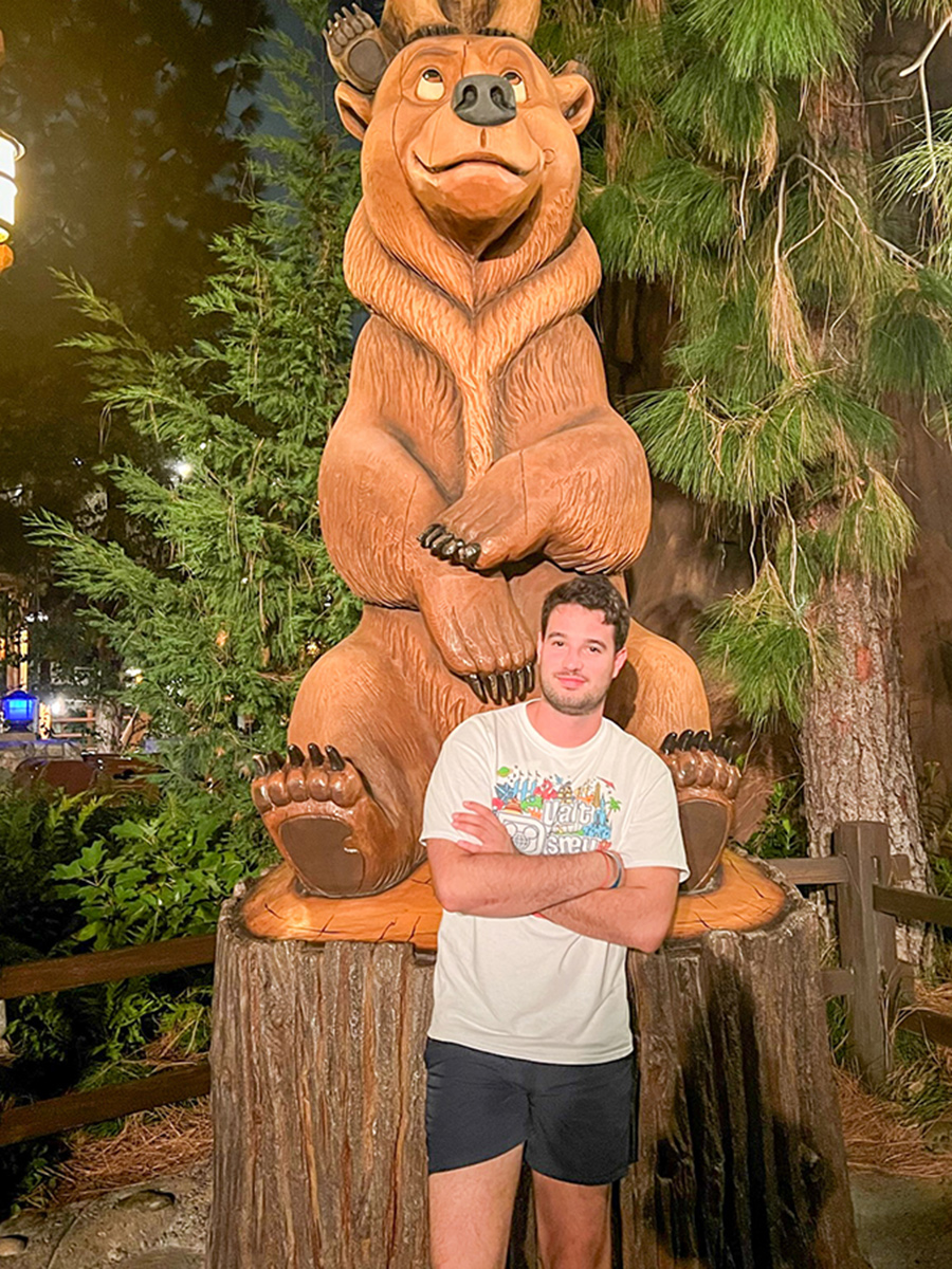 Man posing in front of statue.