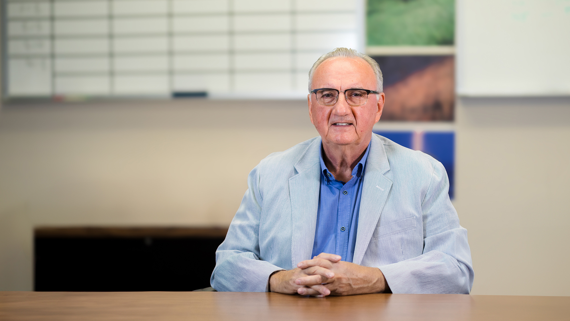 Man in glasses seated at a table.