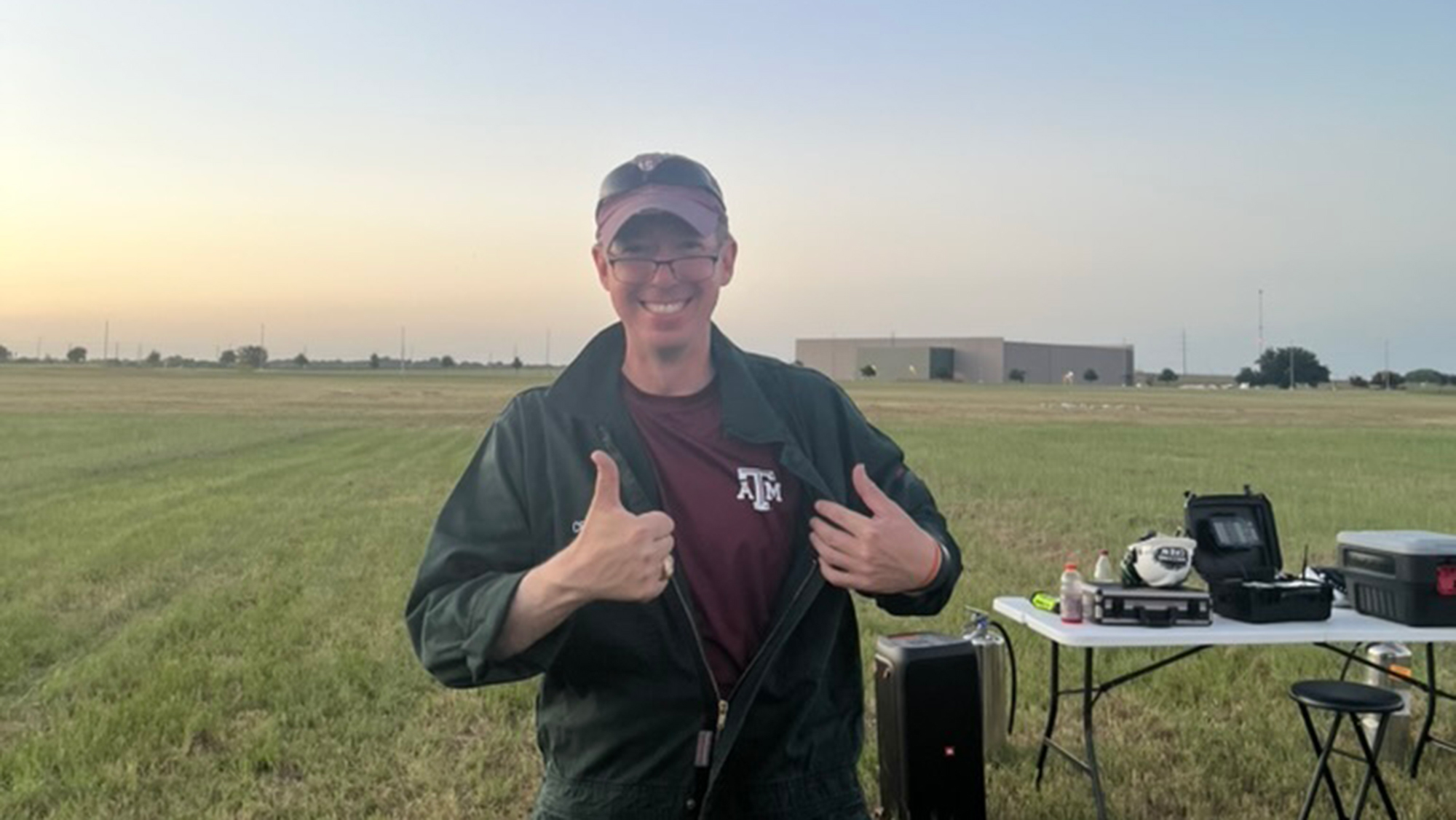 Man in a field holding a thumb up.