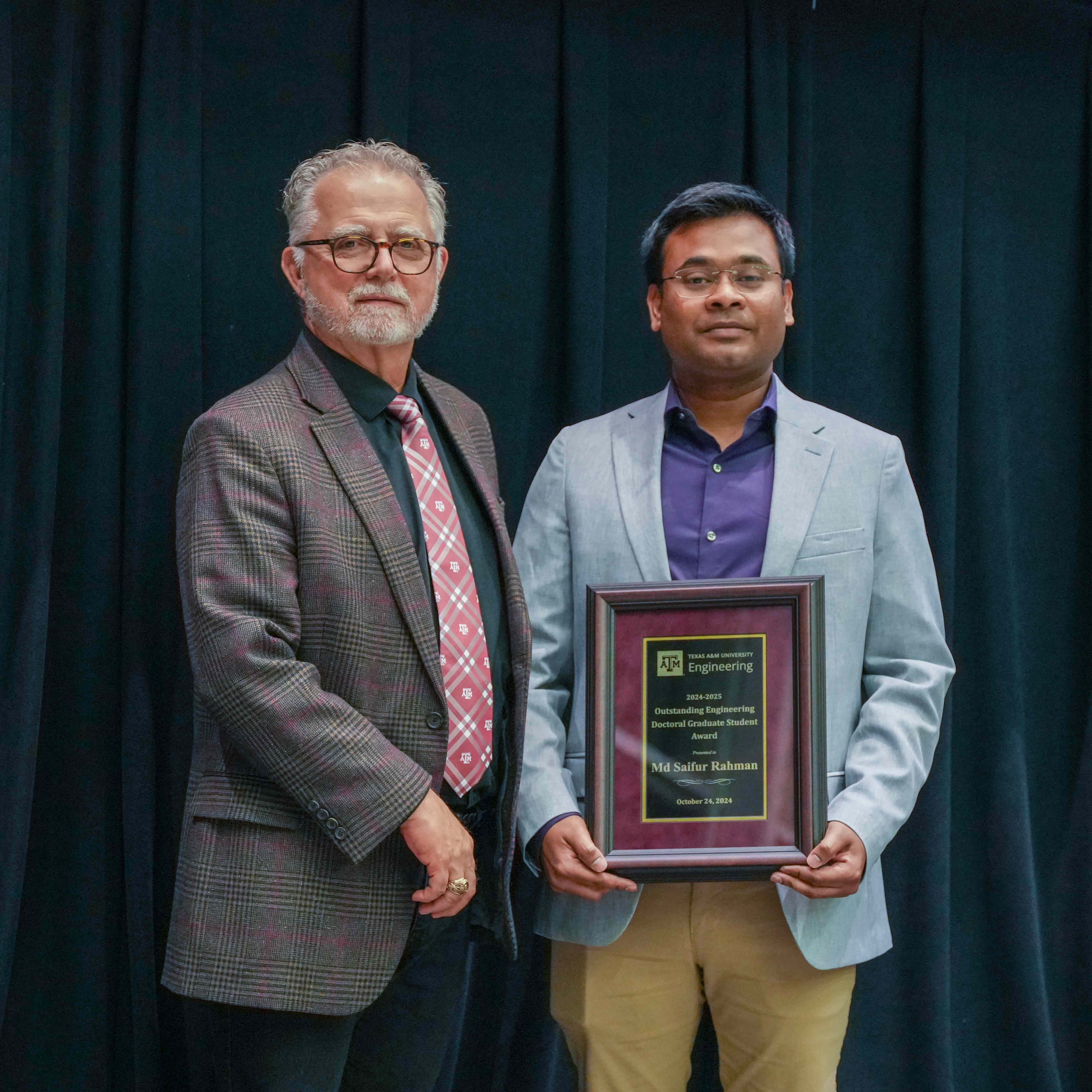 Two men standing, one with a plaque.