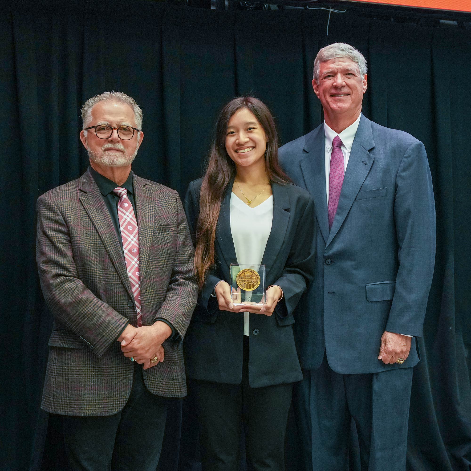 Two men standing next to woman with an award.