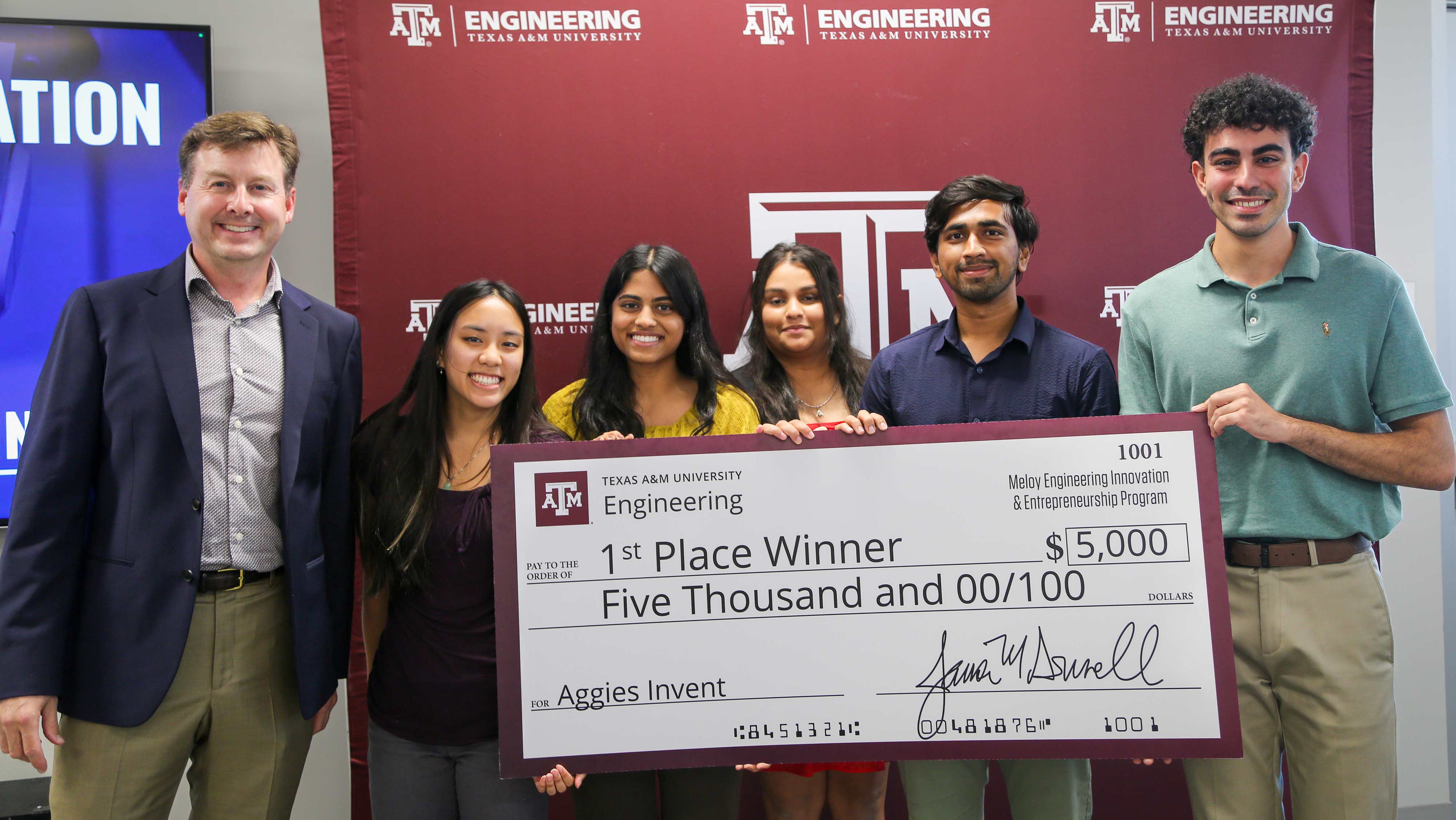 Six people hold a large check for $5,000.