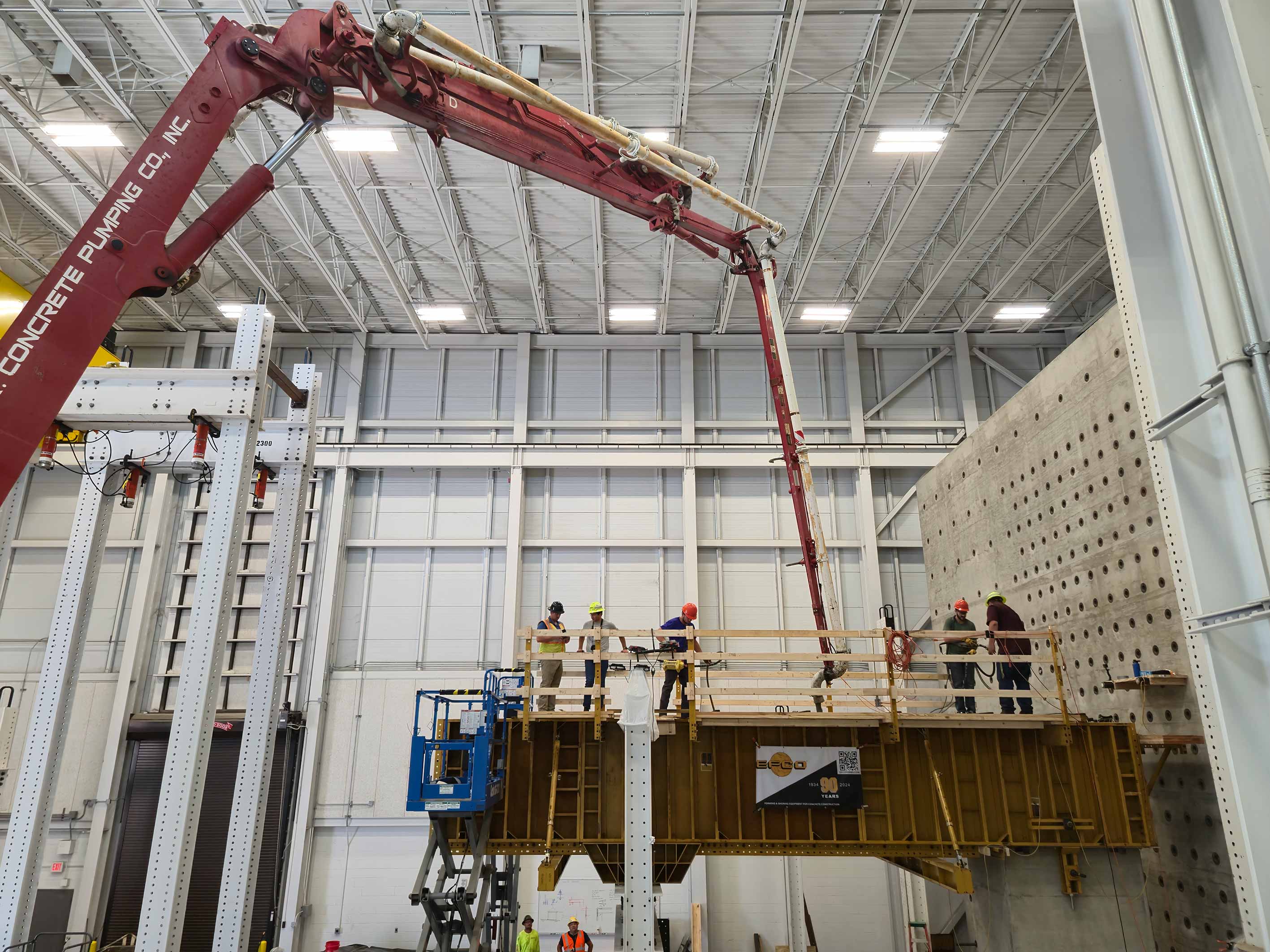 Researchers use a crane to pour concrete into a large construction mold.