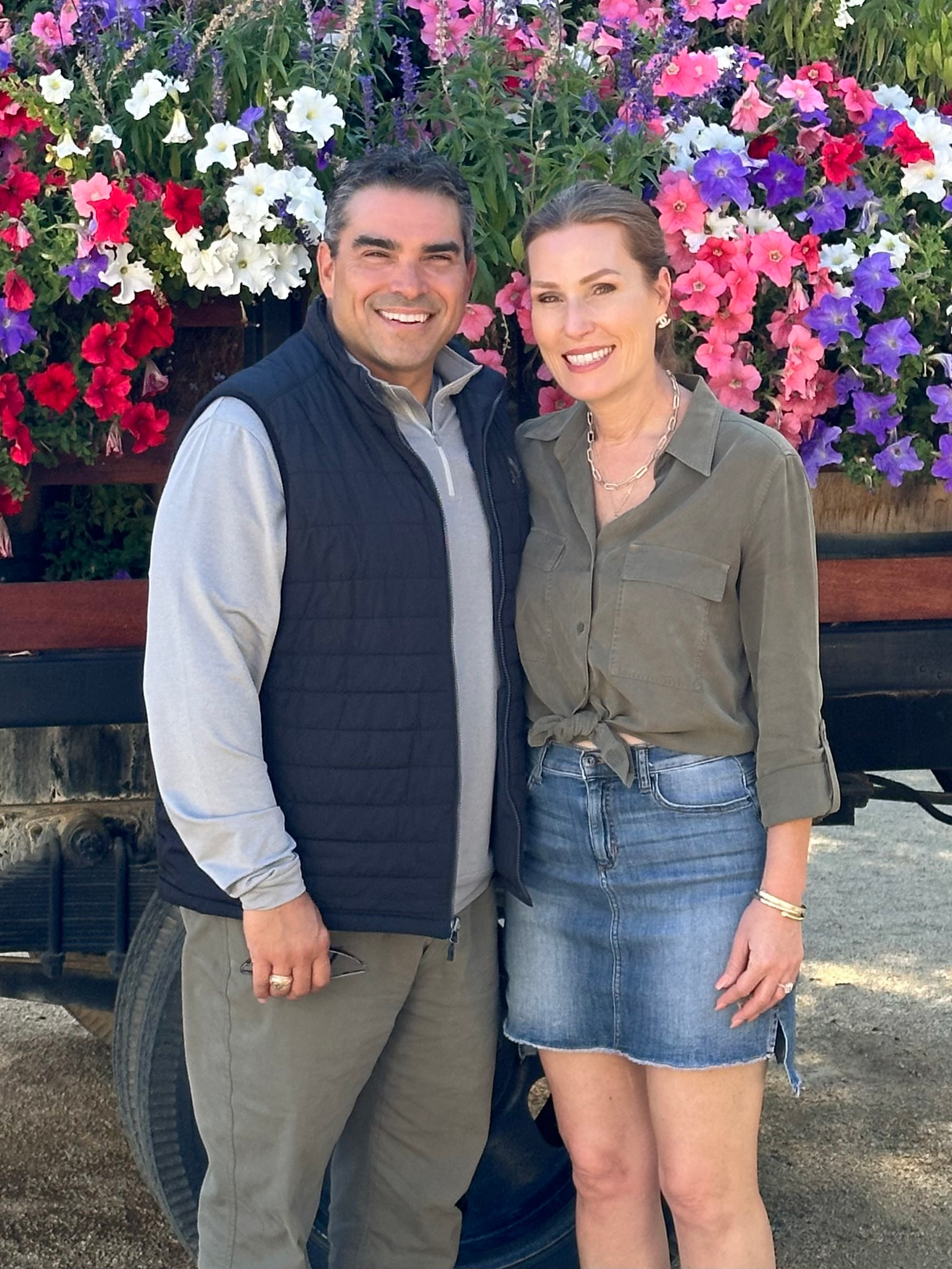 Man and woman in front of flowers. 