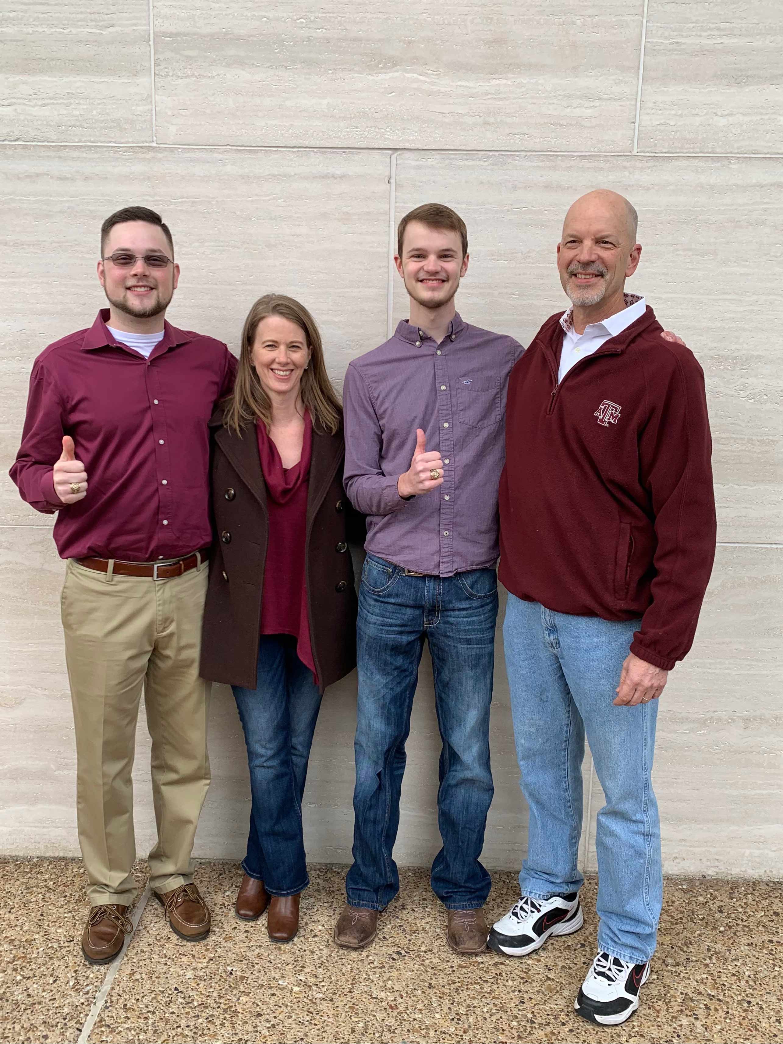 A family of four giving a thumbs-up.