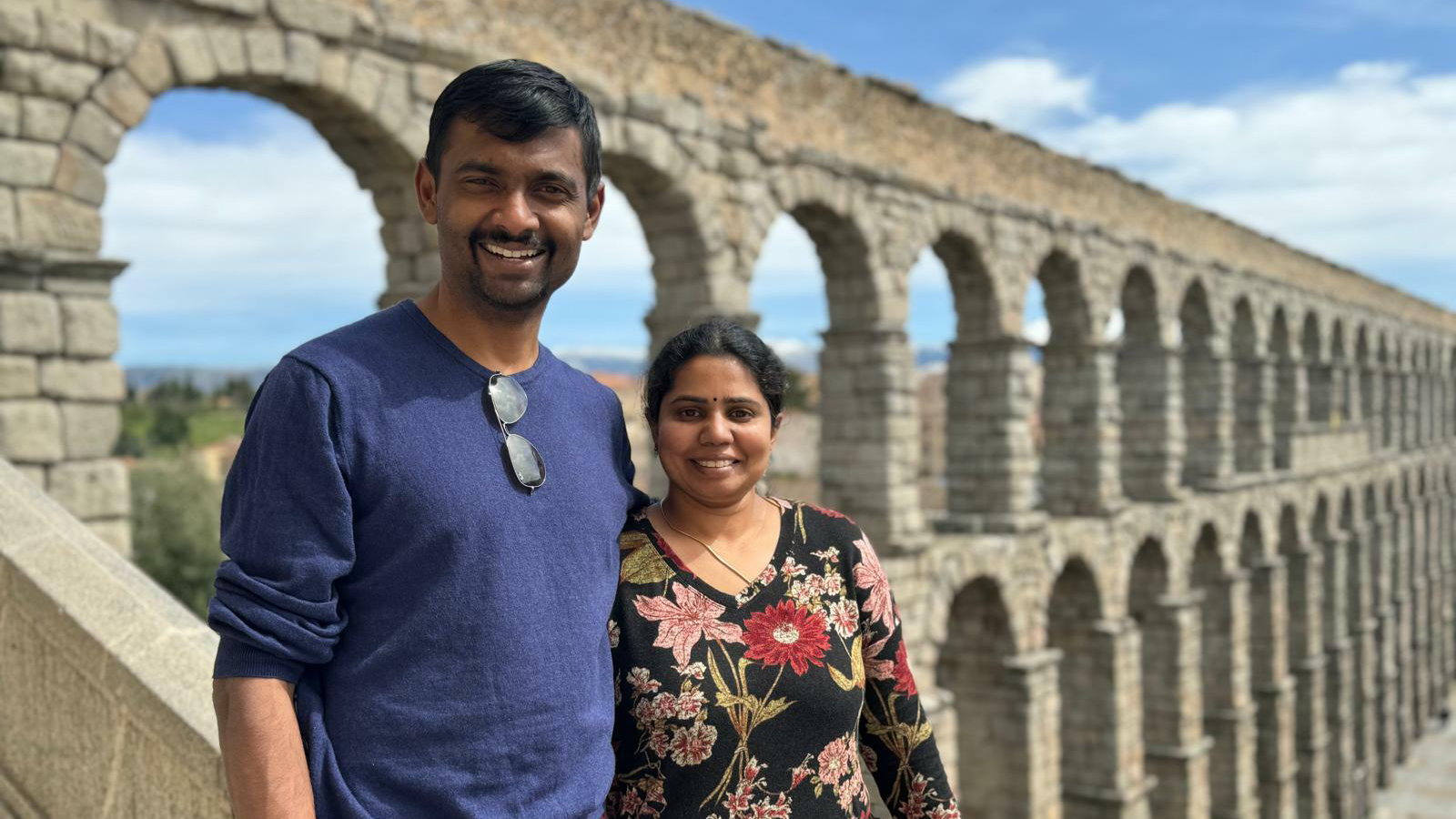 A man and woman pose on a stone staircase at a historical site.