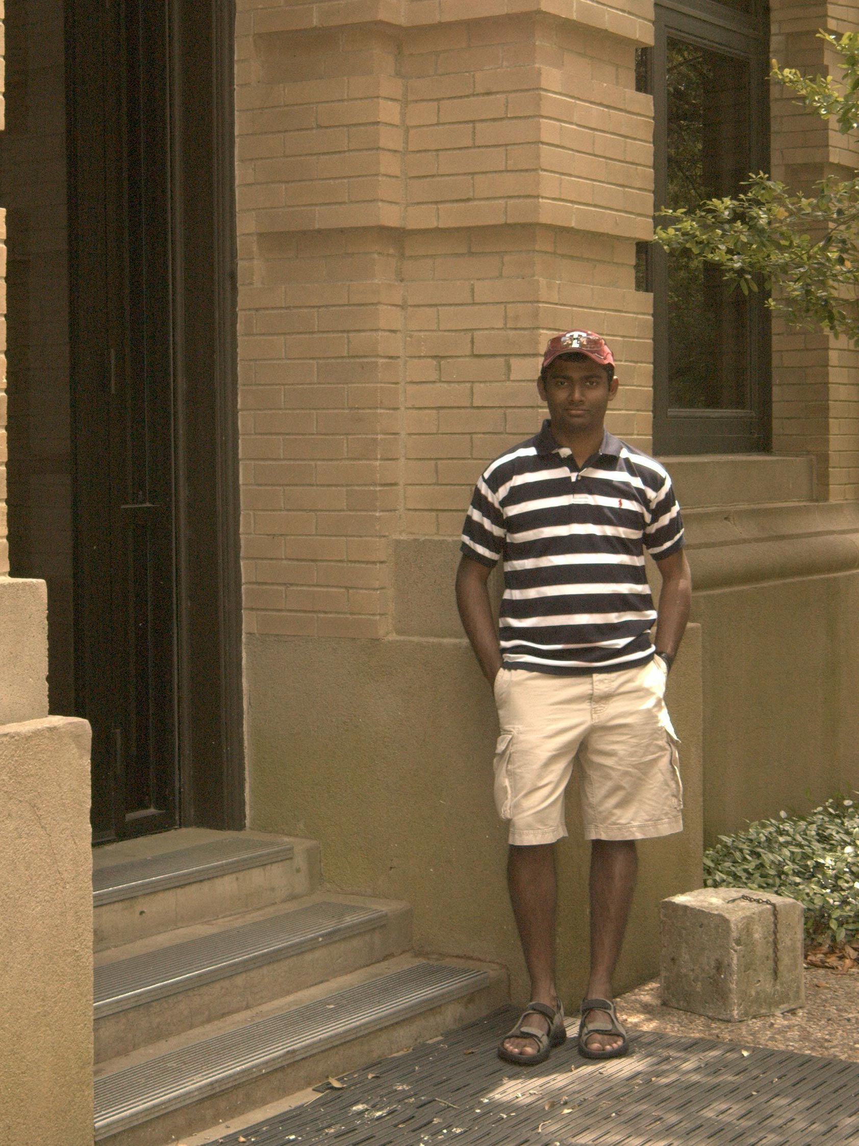 A man in t-shirt and shorts stands in front of a building.