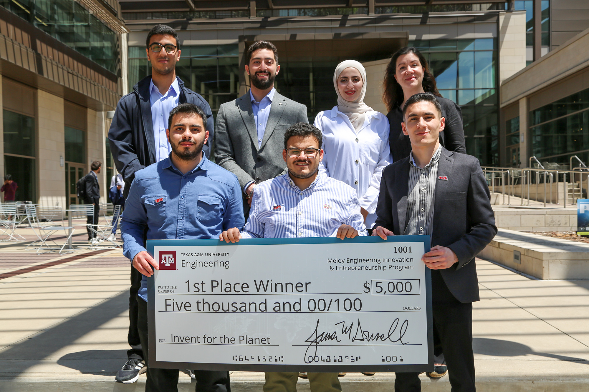 A group of people holding a large check for $5,000.