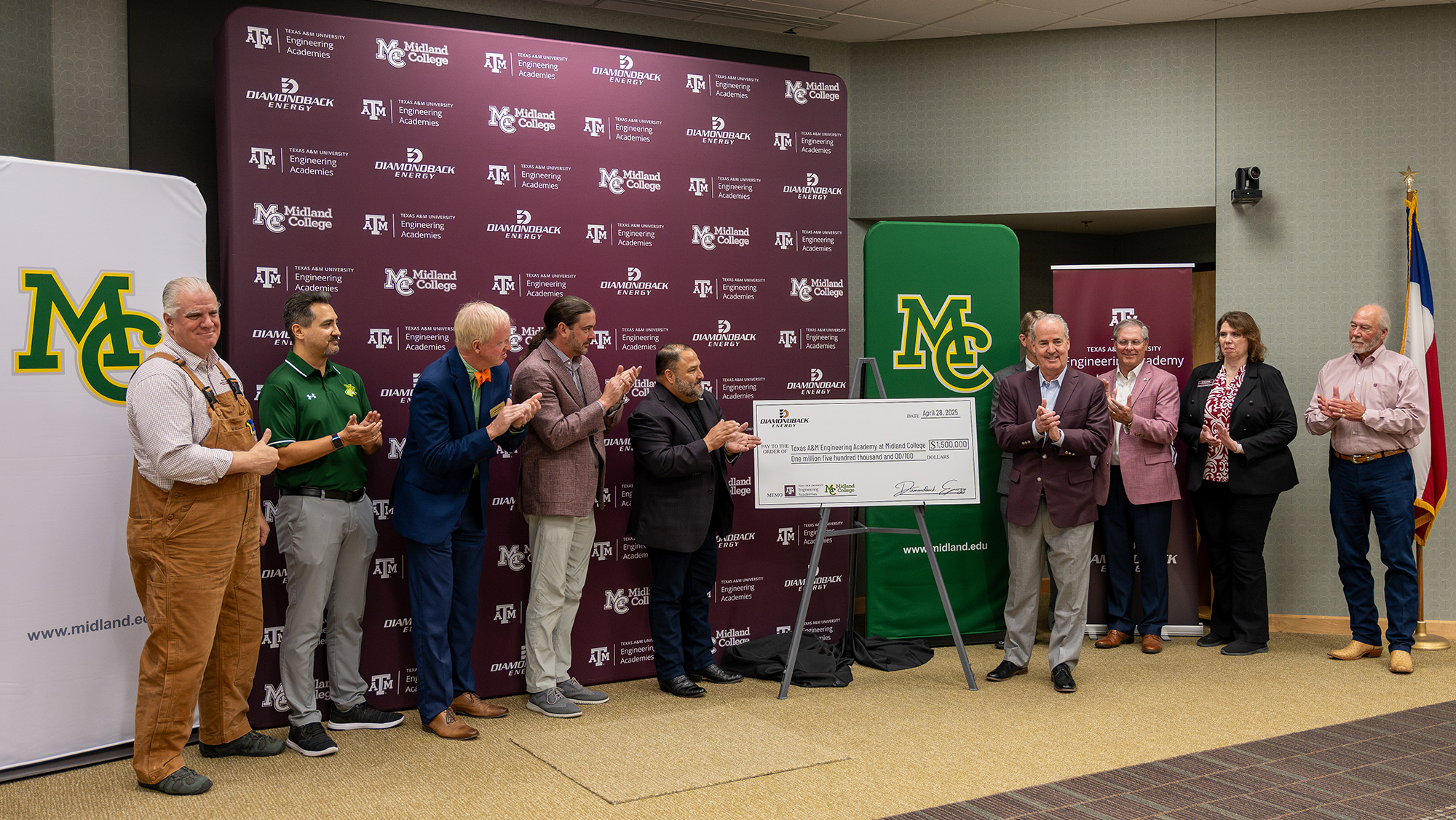 A group of officials clapping or giving a thumbs-up pose alongside a ceremonial check. 