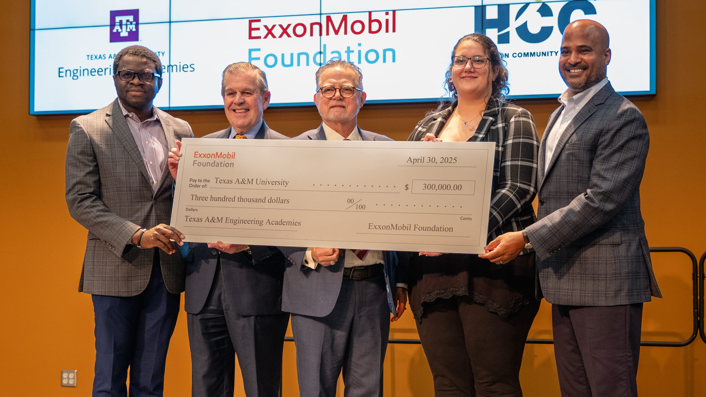 A group of officials pose alongside a ceremonial check.