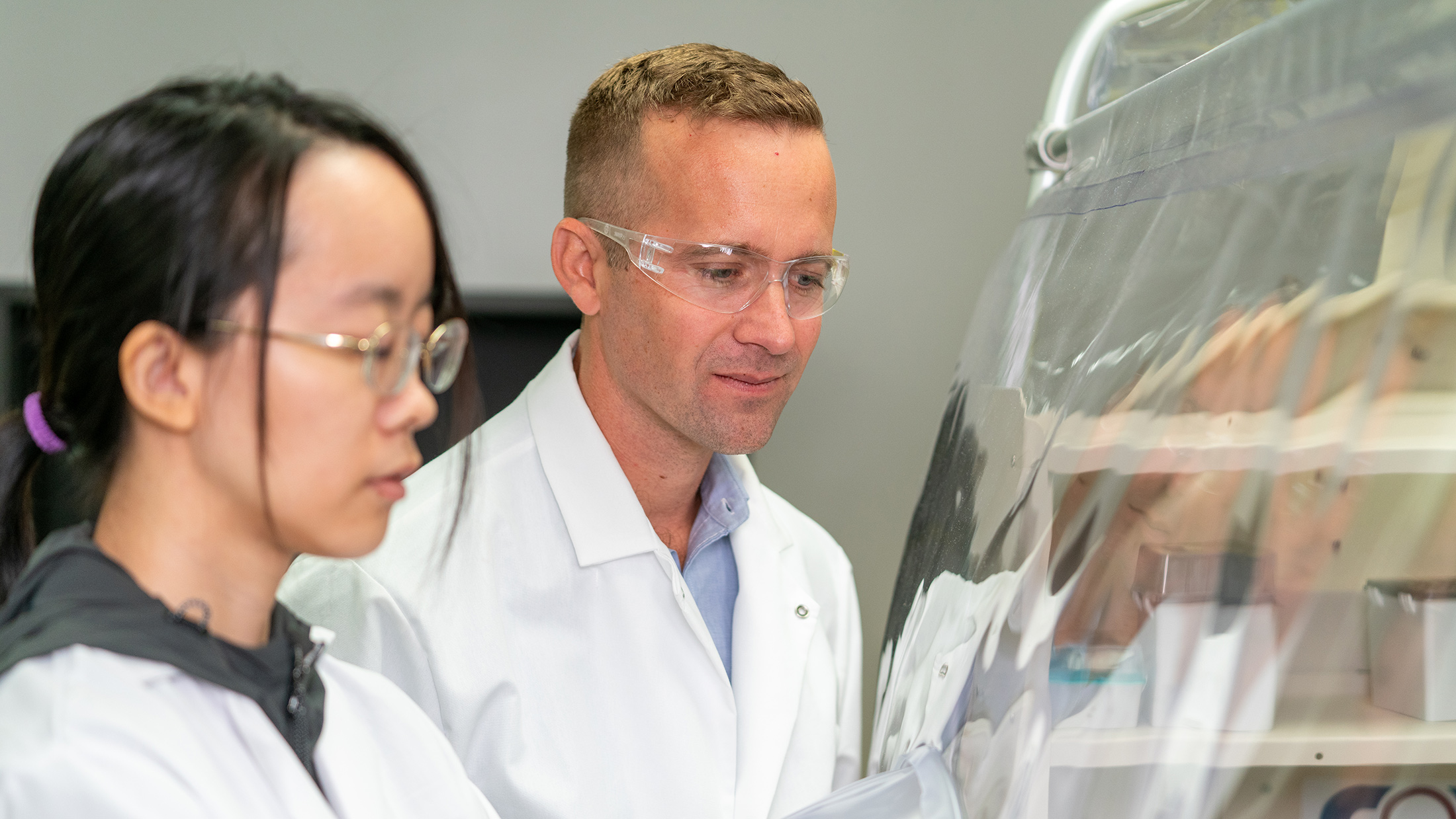 Two people in lab coats working in a lab. 